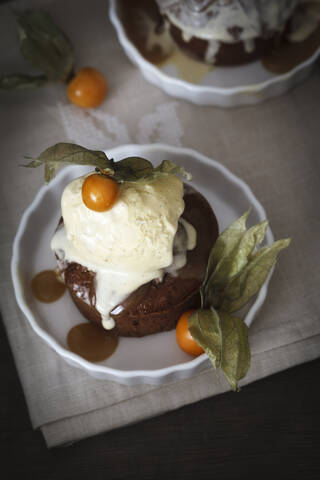 Sticky Toffee Pudding mit Vanilleeis und Physalis im Teller, lizenzfreies Stockfoto