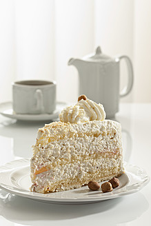 Scheibe Nuss-Sahne-Torte auf Teller, Teekanne und Tasse im Hintergrund - CSF016168