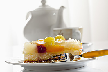 Teller mit Obstkuchen und Teekanne mit Tasse im Hintergrund, Nahaufnahme - CSF016159