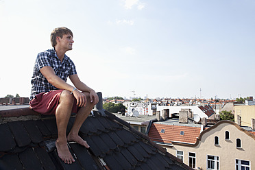 Deutschland, Berlin, Mann sitzt auf Dach - RB001163