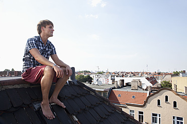 Germany, Berlin, Man sitting on roof - RB001163