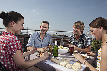 Deutschland, Berlin, Männer und Frauen beim Grillen auf der Dachterrasse, lächelnd - RBF001169