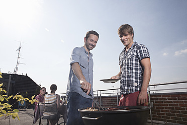 Deutschland, Berlin, Männer grillen am Grill, lächelnd - RBF001171