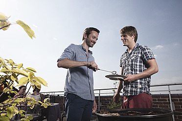 Deutschland, Berlin, Männer grillen am Grill, lächelnd - RBF001172