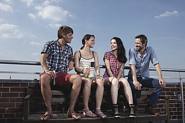 Germany, Berlin, Men and women sitting on roof terrace, smiling - RBF001174