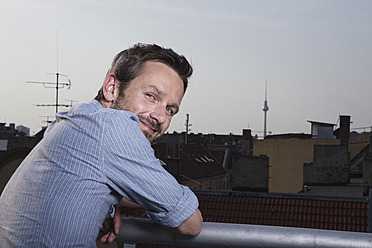 Deutschland, Berlin, Porträt eines Mannes auf der Dachterrasse, lächelnd - RBF001180