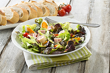 Plate of salad with ham and cheese and bread in tray on table, close up - MAEF005589