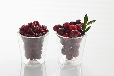 Glas mit frischen und getrockneten Preiselbeeren auf weißem Hintergrund, Nahaufnahme - CSF016264