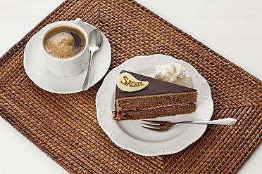 Plate of Sachertorte slice with coffee on straw mat, close up - CSF016290