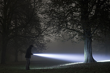 Deutschland, München, Junger Mann mit Taschenlampe in nebliger Nacht - FL000181