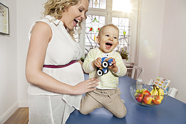 Deutschland, Bonn, Schwangere Mutter spielt mit Sohn im Wohnzimmer, lächelnd - MFF000485