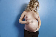 Pregnant woman showing belly and breast stock photo