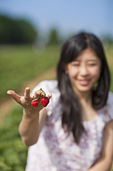 Deutschland, Bayern, Junge Japanerin mit Erdbeeren - FLF000207
