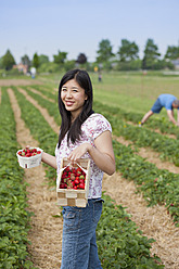 Deutschland, Bayern, Junge Japanerin pflückt Erdbeeren auf einem Feld - FLF000220