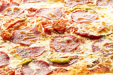 Pizza topped with salami, cheese and peppers on baking tray, close up - MAEF005675