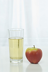 Glas Apfelsaft neben Apfel auf Tisch vor weißem Hintergrund, Nahaufnahme - ASF004774