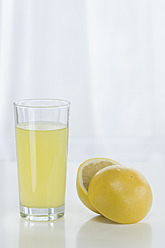 Glas Grapefruitsaft neben Grapefruit vor weißem Hintergrund, Nahaufnahme - ASF004777