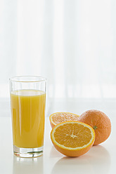 Glas Orangensaft mit Orangen auf dem Tisch vor weißem Hintergrund, Nahaufnahme - ASF004780