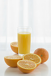 Glas Orangensaft mit Orangen auf dem Tisch vor weißem Hintergrund, Nahaufnahme - ASF004781