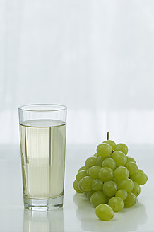 Glas Traubensaft mit Trauben auf dem Tisch vor weißem Hintergrund, Nahaufnahme - ASF004785