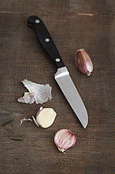 Knoblauchzehe mit Messer auf Holztisch, Nahaufnahme - EVGF000046