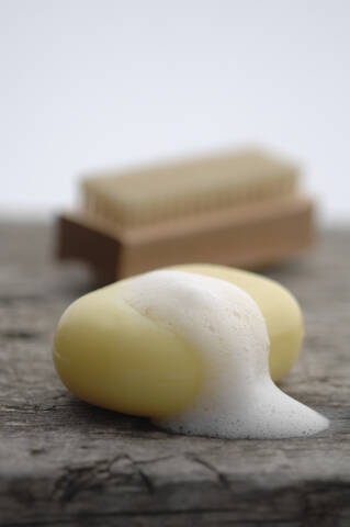 Bar of soap with soap sud and nail brush on wooden table stock photo
