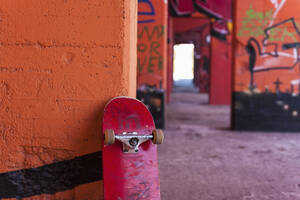 Deutschland, Nordrhein-Westfalen, Duisburg, Skateboard gegen mit Graffiti besprühte Wand - KJF000185