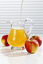 Apfelsaft wird neben Äpfeln in einen Krug gegossen - CSF016392