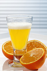 Glas Orangenlimonade neben Orangen auf dem Tisch, Nahaufnahme - CSF016405