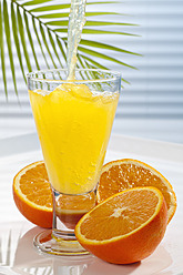 Orangenlimonade wird neben Orangen in ein Glas gegossen, Nahaufnahme - CSF016406