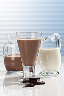 Glas und Karaffen mit Schokoladenmilch und Schokoladenstückchen, Nahaufnahme - CSF016429