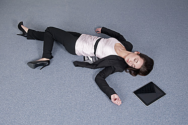 Germany, Berlin, Exhausted businesswoman lying on floor beside digital tablet - BFRF000161