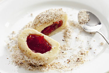 Curd cheese dumpling with strawberry filling and grounded hazelnut on plate, close up - CSF016485