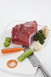 Rohes Stück Rindfleisch mit Gemüse auf Schneidebrett, Nahaufnahme - CSF016505