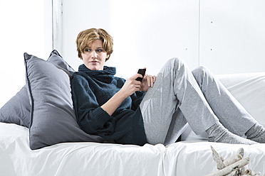 Young woman using mobile on couch - MAEF005746