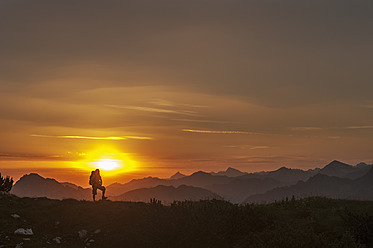 Österreich, Salzburger Land, Mann wandert bei Sonnenaufgang durch die Niederen Tauern - HHF004303