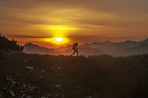 Österreich, Salzburger Land, Mann wandert bei Sonnenaufgang durch die Niederen Tauern - HHF004304