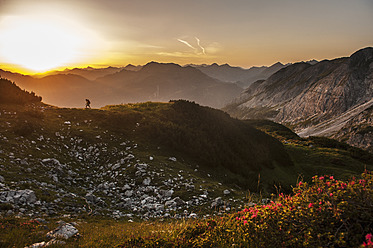 Österreich, Salzburger Land, Mann wandert bei Sonnenaufgang durch die Niederen Tauern - HHF004305