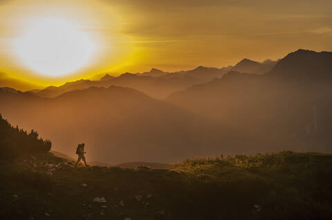 Österreich, Salzburger Land, Mann wandert bei Sonnenaufgang durch die Niederen Tauern, lizenzfreies Stockfoto