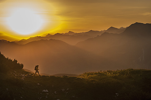 Österreich, Salzburger Land, Mann wandert bei Sonnenaufgang durch die Niederen Tauern - HHF004307