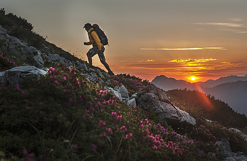 Österreich, Salzburger Land, Mann wandert bei Sonnenaufgang durch die Niederen Tauern - HHF004310