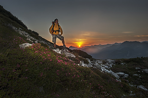Österreich, Salzburger Land, Mann wandert bei Sonnenaufgang durch die Niederen Tauern - HHF004311