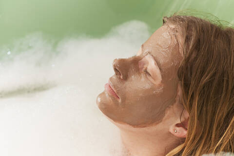 Mid adult woman with mud mask in bathtub, close up stock photo