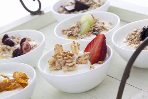 Schalen mit Joghurt, Müsli und Früchten auf einem Holztablett, lizenzfreies Stockfoto
