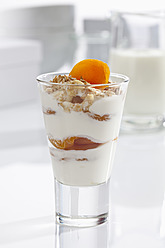 Glass of yogurt with muesli, fruit and cornflakes on white background, close up - CSF016585