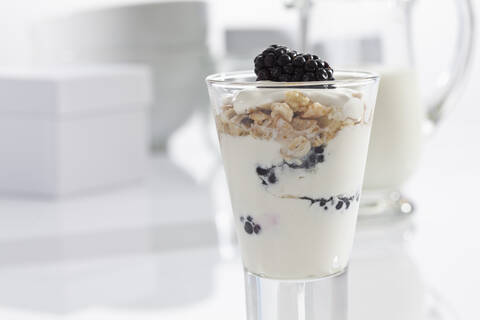 Glas Joghurt mit Müsli, Brombeeren und Cornflakes auf weißem Hintergrund, Nahaufnahme, lizenzfreies Stockfoto