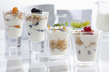 Gläser mit Joghurt, Müsli, Cornflakes und Früchten auf weißem Hintergrund, Nahaufnahme - CSF016589