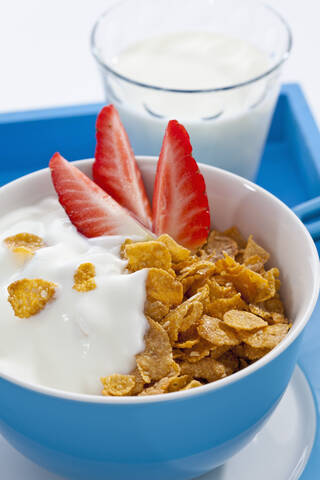 Schale mit Kornblumen und Erdbeeren und Glas Milch auf weißem Hintergrund, lizenzfreies Stockfoto