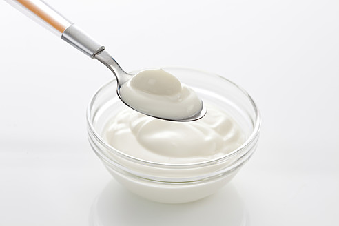 Schüssel und Löffel mit Joghurt auf weißem Hintergrund, Nahaufnahme - CSF016606