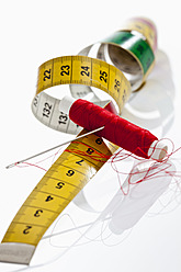 Needle, thread and measure tape on white background, close up - CSF016614